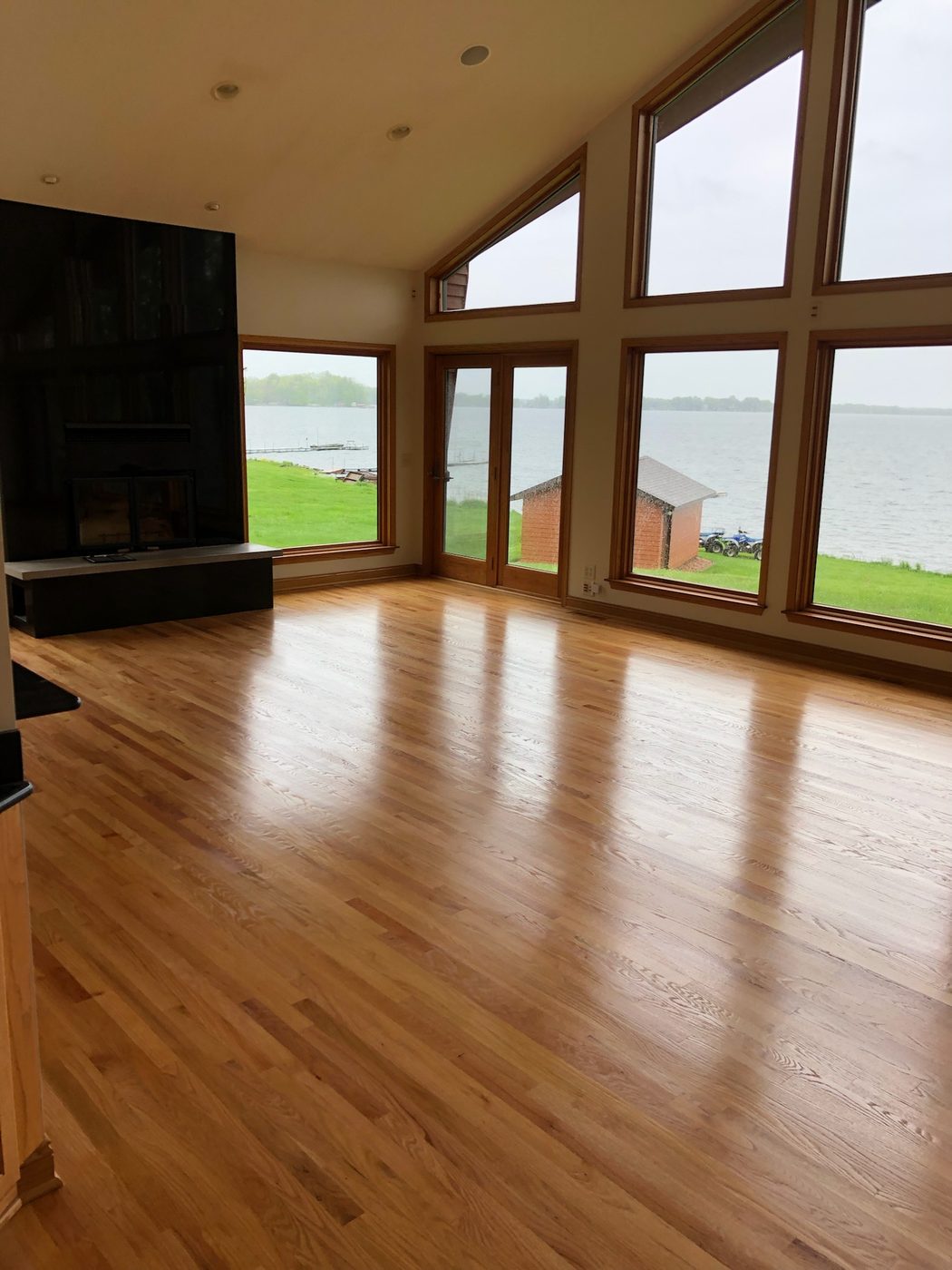 Hardwood refinish in lakefront room with floor-to-ceiling windows