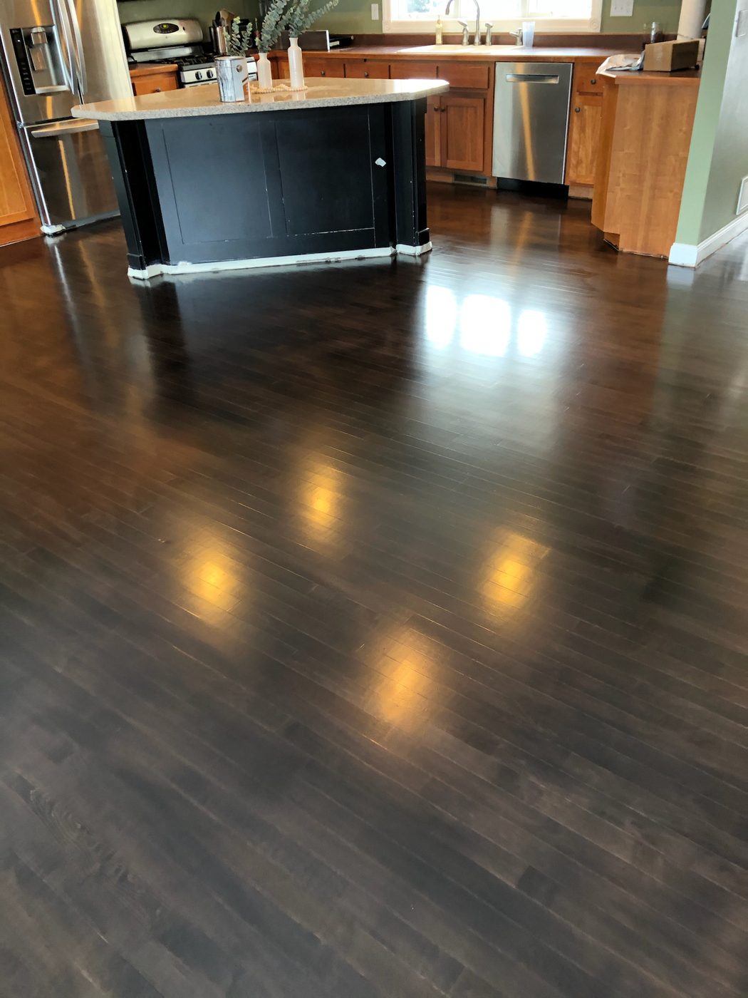 Dark hardwood in open-concept kitchen with black island and high-gloss finish